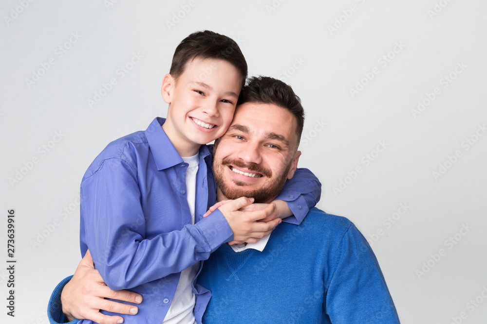 Cheerful dad and son embracing and smiling at camera Cheerful dad and son embracing and smiling at camera