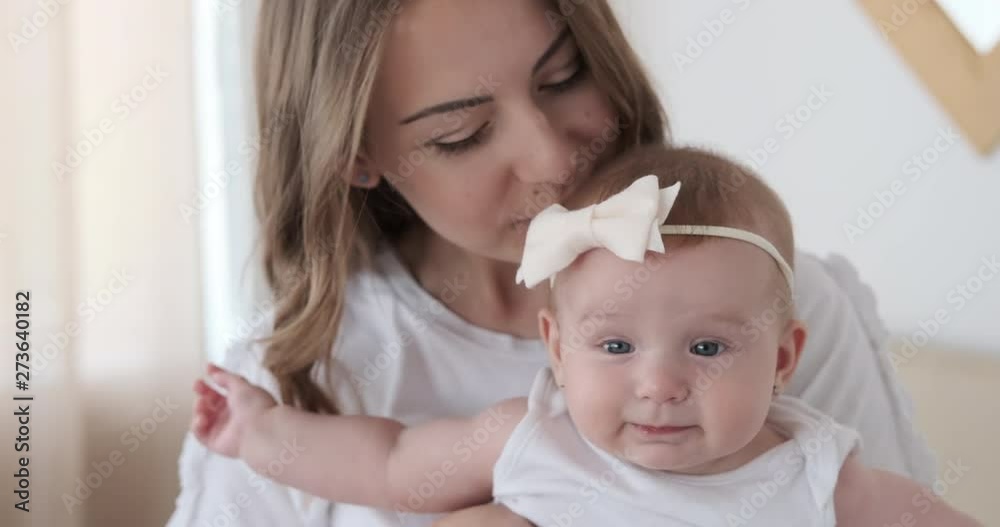 Happy mother kissing her cute baby daughter at home Happy mother kissing her cute baby daughter at home
