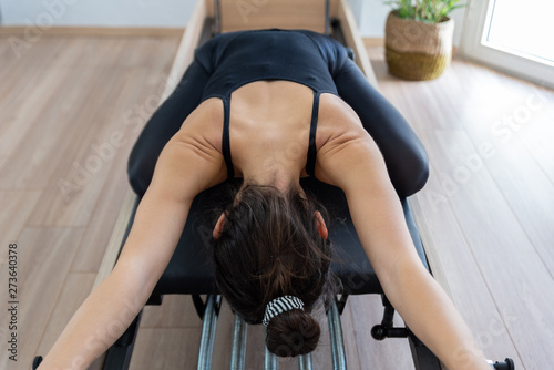 Young woman exercising on pilates reformer bed