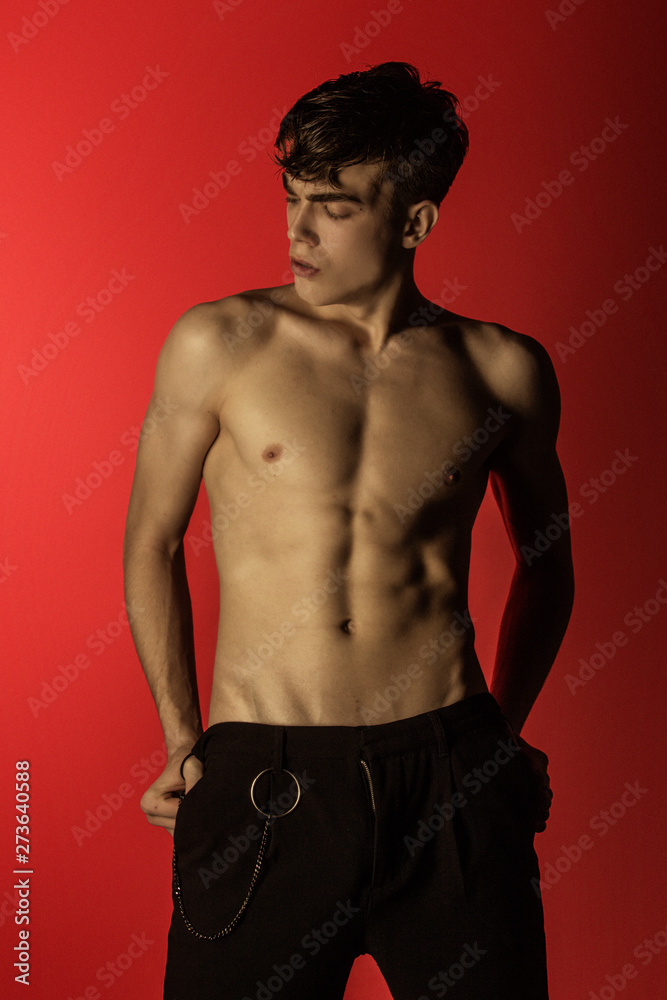 Muscle strong beautiful stripped male model in denim black jeans on red isolated font background Muscle strong beautiful stripped male model in denim black jeans on red isolated font background