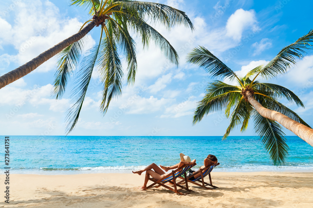 Couple relax on the beach enjoying beautiful sea on the tropical island - obrazy, fototapety, plakaty 