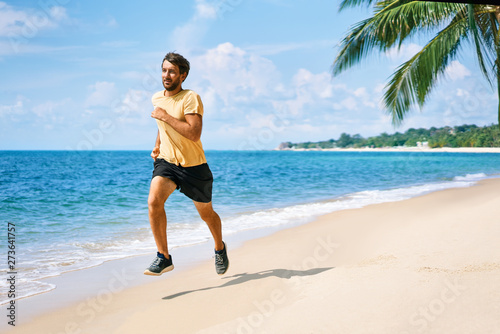 Young man running on the sea shore of tropical beach