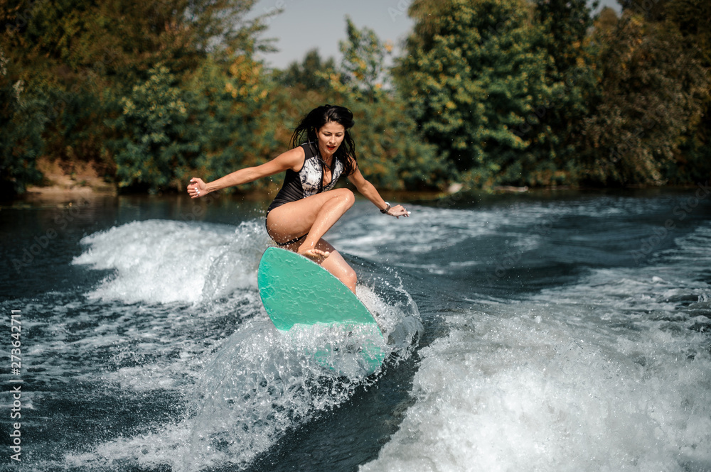 Fototapeta premium Sporty surfgirl on a surfboard near seashore