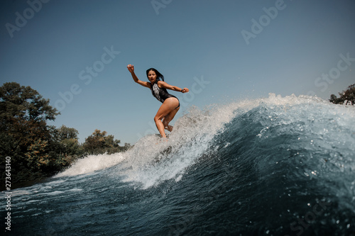 Brunette woman surfs on surfboard in sea