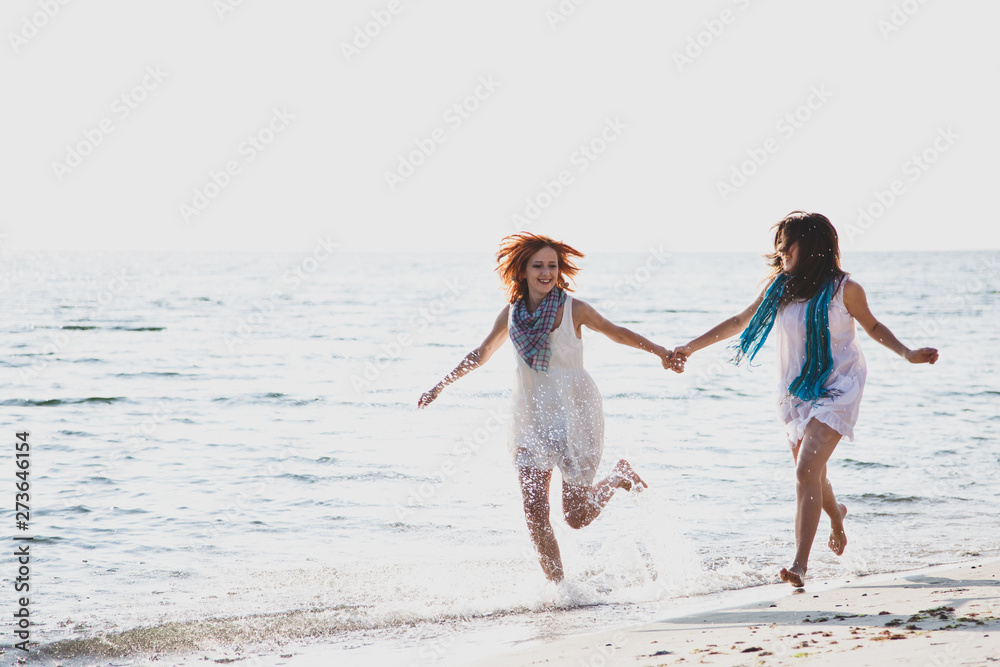 Two beautiful girls running on the beach.