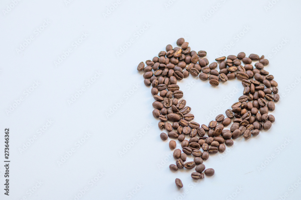 Ein Haufen geröstete Kaffeebohnen mit einem Loch in Herzform auf weißem Hintergrund lädt zum Kaffeegenuss ein Ein Haufen geröstete Kaffeebohnen mit einem Loch in Herzform auf weißem Hintergrund lädt zum Kaffeegenuss ein