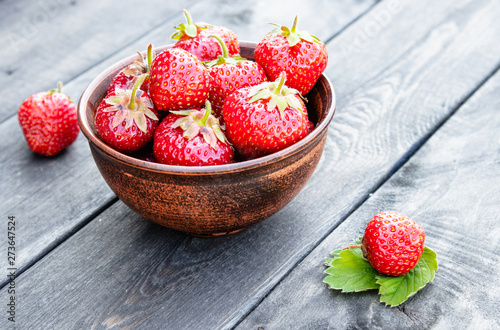 Fresh strawberries in a bowl on a wooden table.
