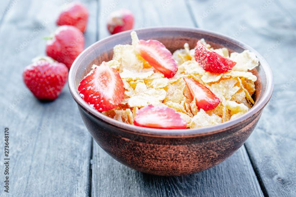 Fresh homemade muesli, muesli with strawberries in a plate on a dark gray background, selective focus Fresh homemade muesli, muesli with strawberries in a plate on a dark gray background, selective focus