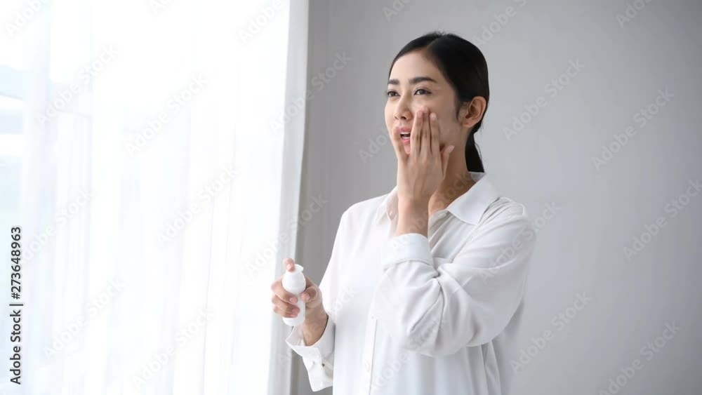 Beauty concept. Asian girls are applying skin cream in the room.