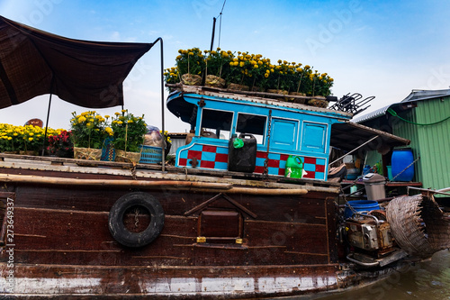 Fotografie Close-up of a brown and blue boat or sampan carrying yellow and red flowers for Tet New Year Celebration, Mekong Delta, Vietnam