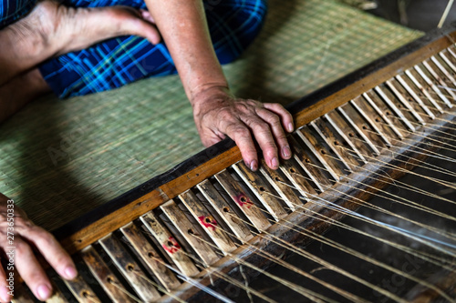 Close-up on the hands of an old woman weaving sedge mat in Ben Tre, Mekong delta region, Vietnam.