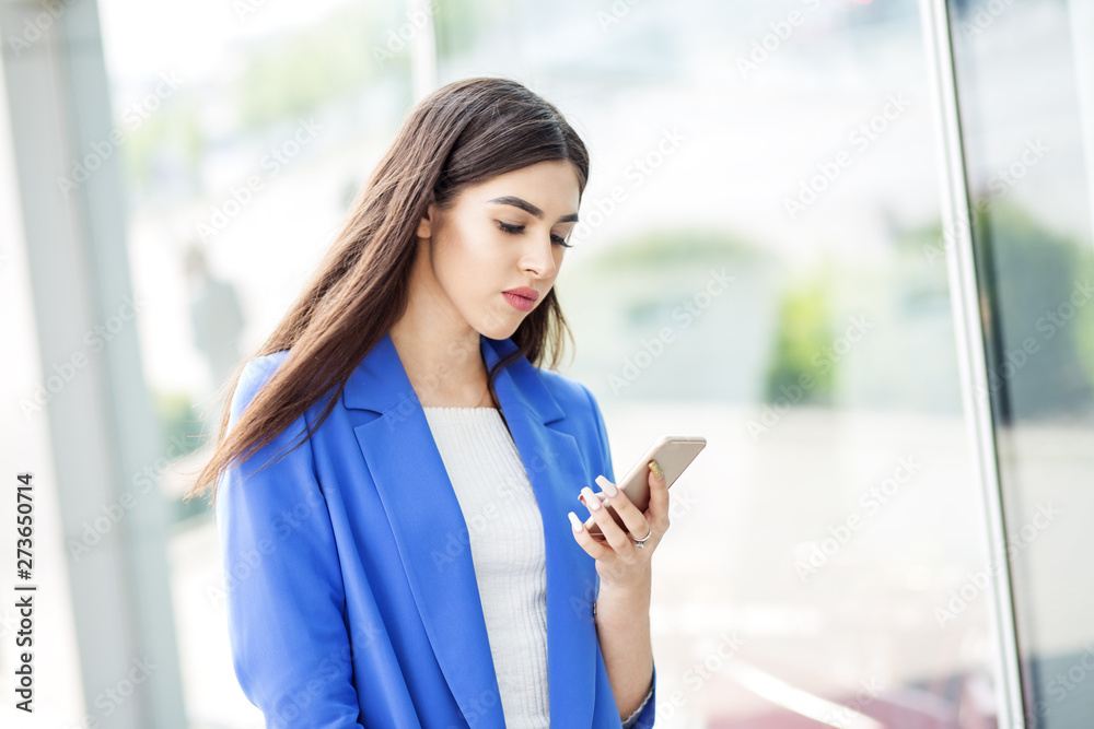 Beautiful young woman uses the Internet on the phone. The concept of fashion, business, communication and lifestyle Beautiful young woman uses the Internet on the phone. The concept of fashion, business, communication and lifestyle