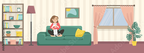 Happy girl hugs cute cat on the home sofa. Unhappy cat. Cozy home.