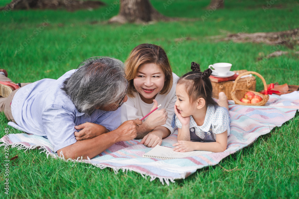 Asian grandparents and granddaughter are lying on the grass field outdoor, asian family concept Asian grandparents and granddaughter are lying on the grass field outdoor, asian family concept