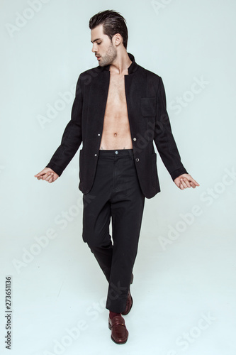 Muscle strong beautiful stripped male model in black toxedo and black trousers on grey isolated font background photo