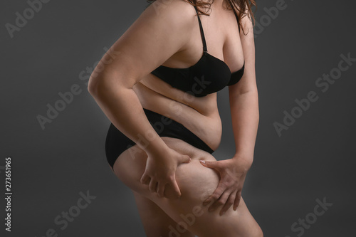 Beautiful plus size woman on grey background. Concept of weight loss