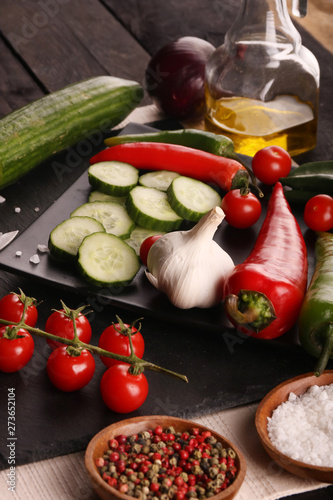 Fototapeta Naklejka Na Ścianę i Meble -  Healthy food. Vegetables on a black plate and stone cutting board and wooden background.
