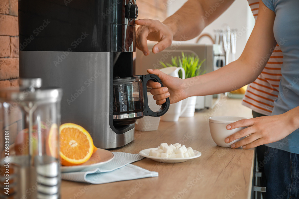 Young couple using coffee machine in kitchen Young couple using coffee machine in kitchen