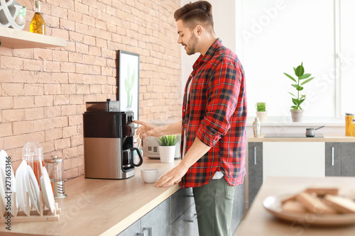 Handsome man using coffee machine in kitchen