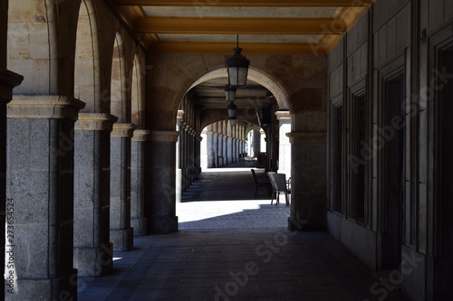 Vista a la sombra a través de los soportales de una plaza.