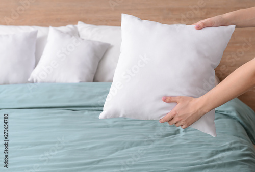 Woman fluffing soft pillows on bed photo