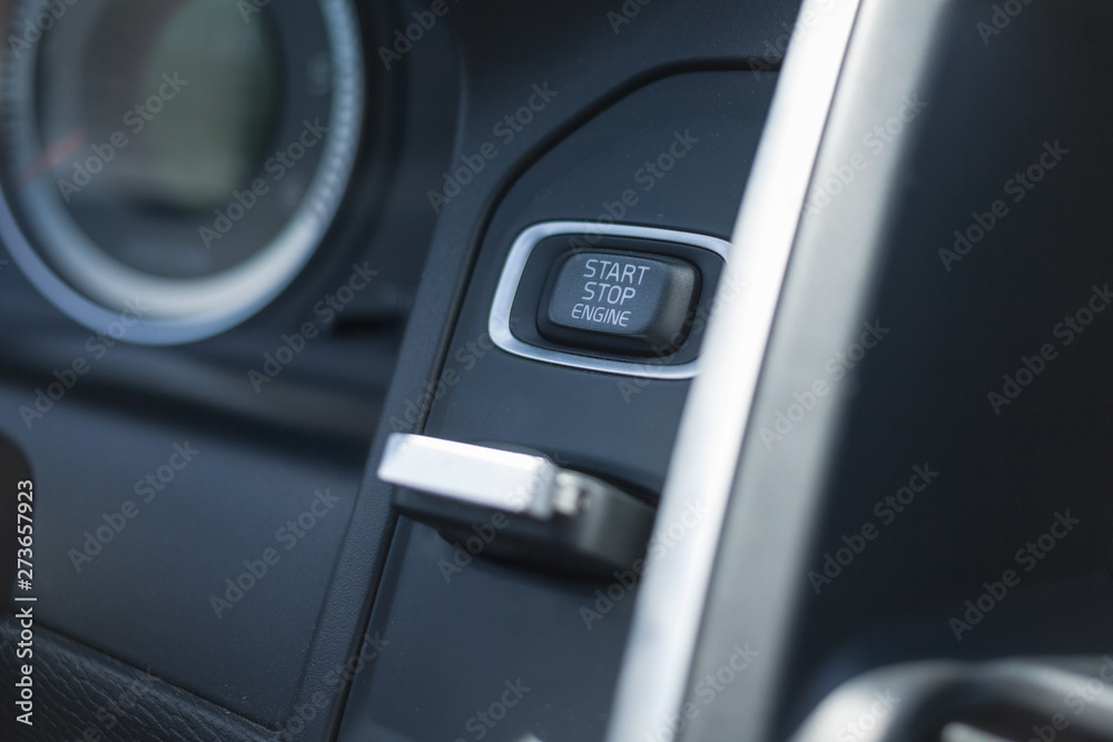 Car key in keyhole for ignition. Car key in ignition about to start the car. Close up of start-stop button. .
