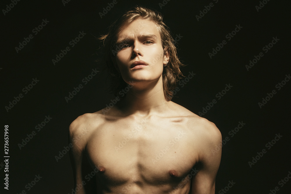 Muscle blonde beautiful stripped male model with long hair portrait in water drops on black isolated font background Muscle blonde beautiful stripped male model with long hair portrait in water drops on black isolated font background