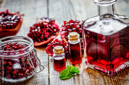 sliced pomegranate and extract in glass on wooden background