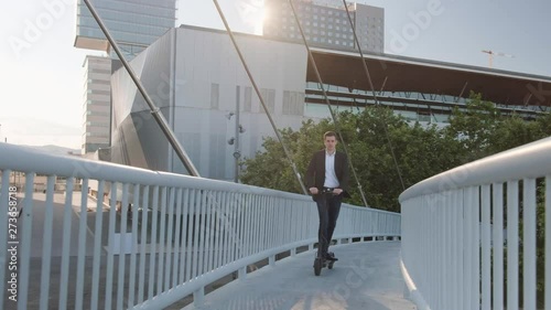 Young businessman riding an electric scooter for a business meeting in the office, office buildings, business man, sunset, electric transport, ecological transport, 4k, e-skateboard
