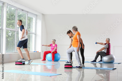 Elderly people training with instructor in gym photo