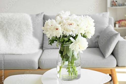 Vase with beautiful peony flowers on table in room