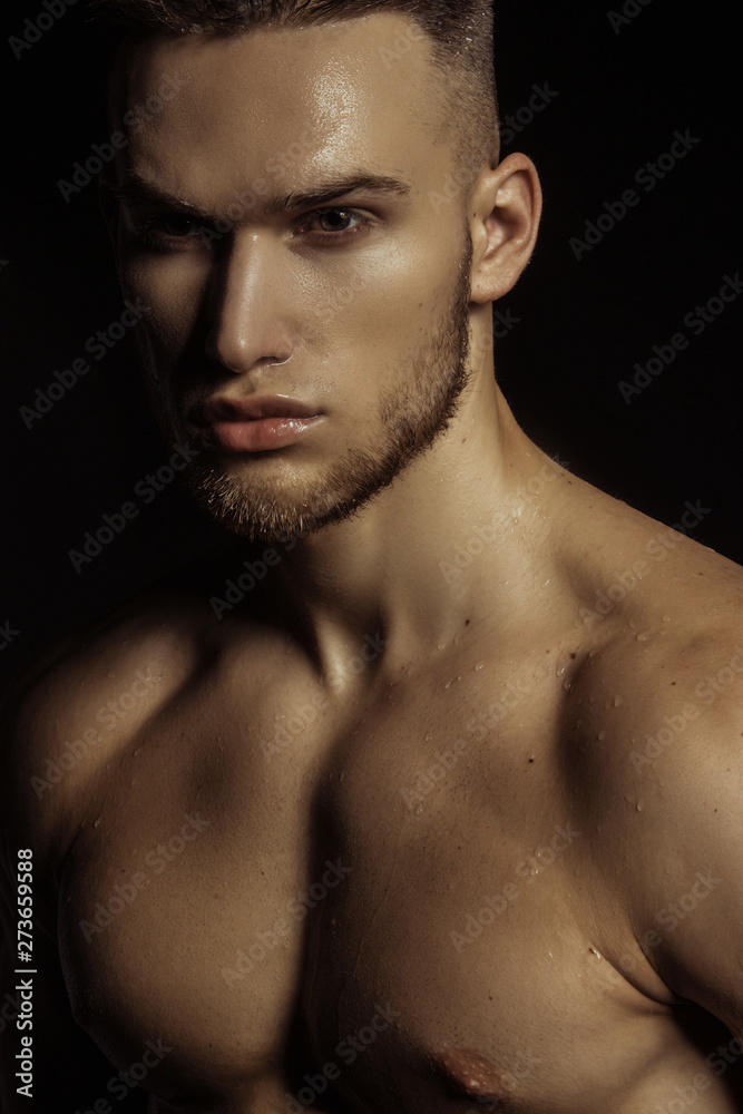 Handsome sport sexy stripped guy portrait in water drops on isolated black background Handsome sport sexy stripped guy portrait in water drops on isolated black background