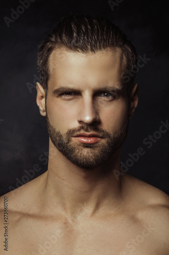 Handsome sport sexy stripped guy portrait in a water draps and fog smoke mist on isolated black background