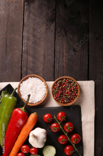 Healthy food. Vegetables on a black plate and stone cutting board and wooden background. Top View and copy space.