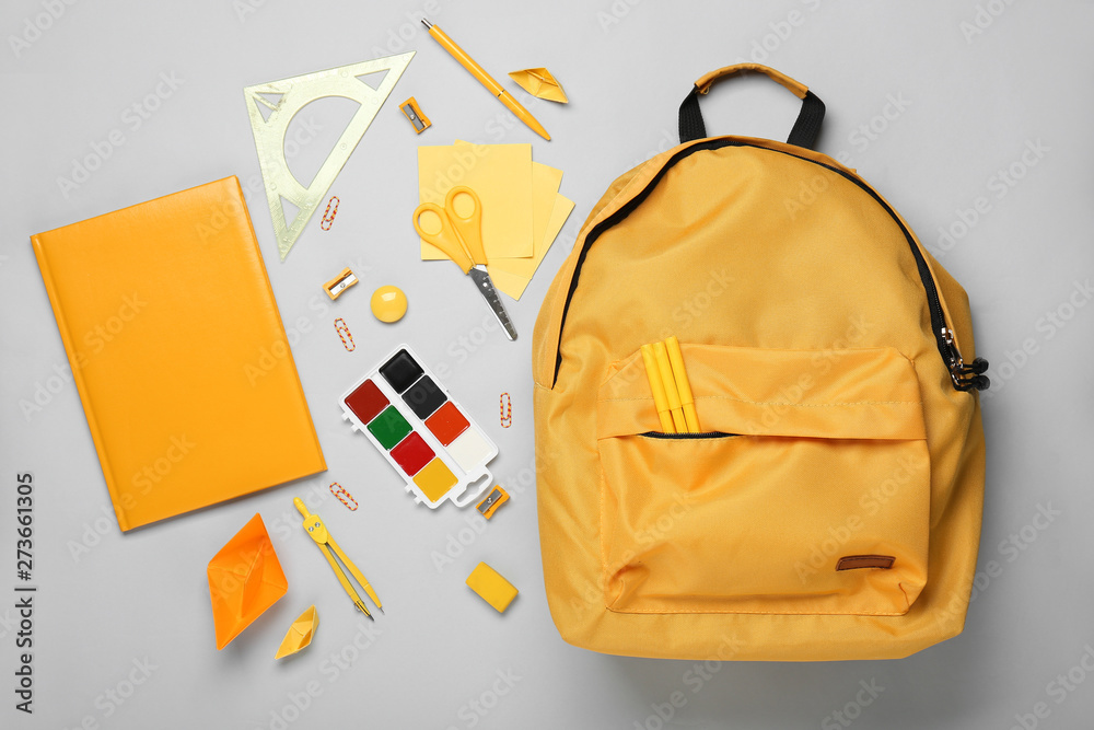 School backpack and stationery on light background - obrazy, fototapety, plakaty 