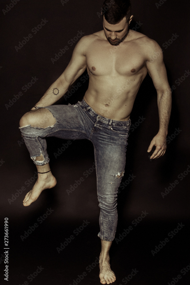 Muscle strong beautiful stripped male model in denim blue jeans on black isolated font background Muscle strong beautiful stripped male model in denim blue jeans on black isolated font background