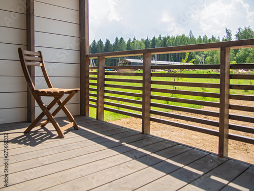 Country house terrace, hotel, garden wooden furniture, a chair. In the background is a green lawn. Horizontal orientation, space for text.