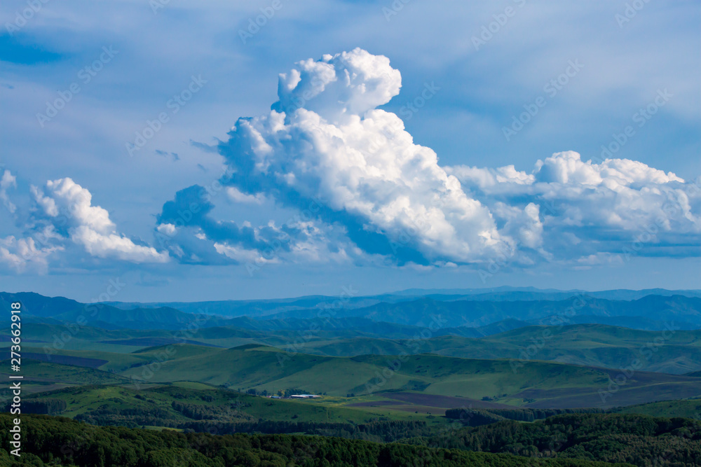 Natural landscape. Beautiful cumulus clouds float above a mountain valley.