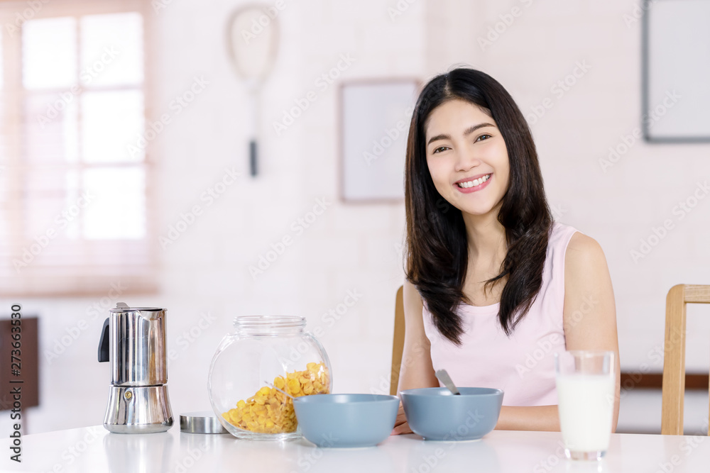 Headshot of young attractive asian woman smiling, looking at camera and sitting on table in living room at home with morning breakfast. Leisure relax lifestyle in weekend day of happy asian girl.