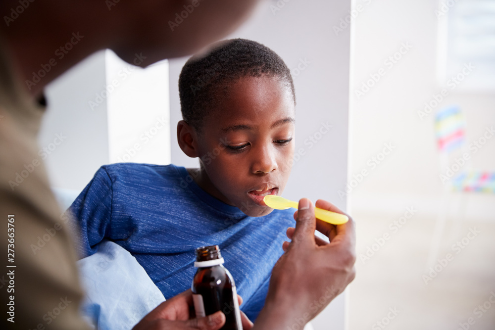 Father Giving Sick Son Ill In Bed Medicine From Bottle Father Giving Sick Son Ill In Bed Medicine From Bottle