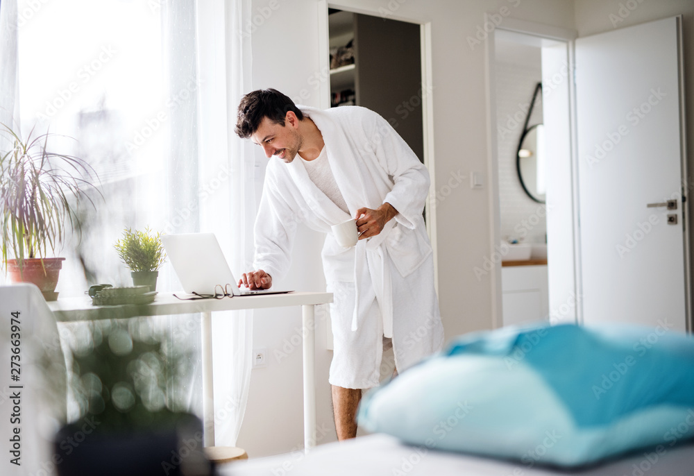Young man with laptop and coffee in the bedroom in the morning. Young man with laptop and coffee in the bedroom in the morning.