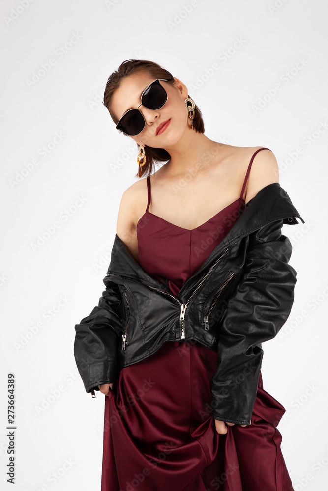 Asian Chinese Fashion influencer modeling in a wine color silk dress and leather jacket isolated in white background Asian Chinese Fashion influencer modeling in a wine color silk dress and leather jacket isolated in white background