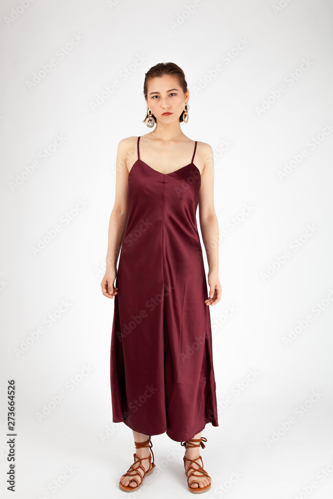 Asian Chinese Fashion influencer modeling in a wine color silk dress isolated in white background Asian Chinese Fashion influencer modeling in a wine color silk dress isolated in white background
