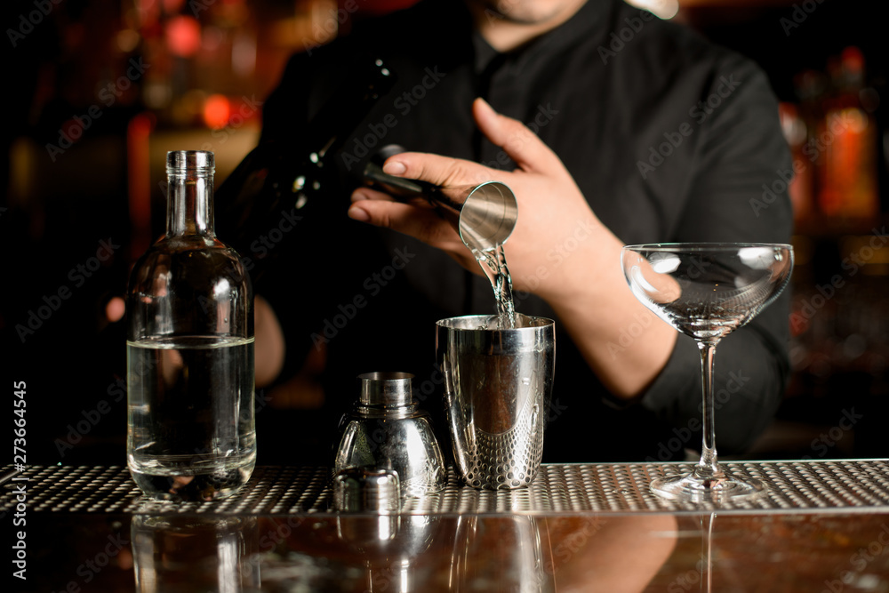 Bartender pouring an alcohol from the steel measuring jigger