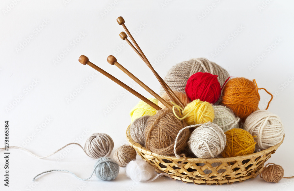 Сolorful balls of wool yarn and knitting wooden needles in a wicker ...