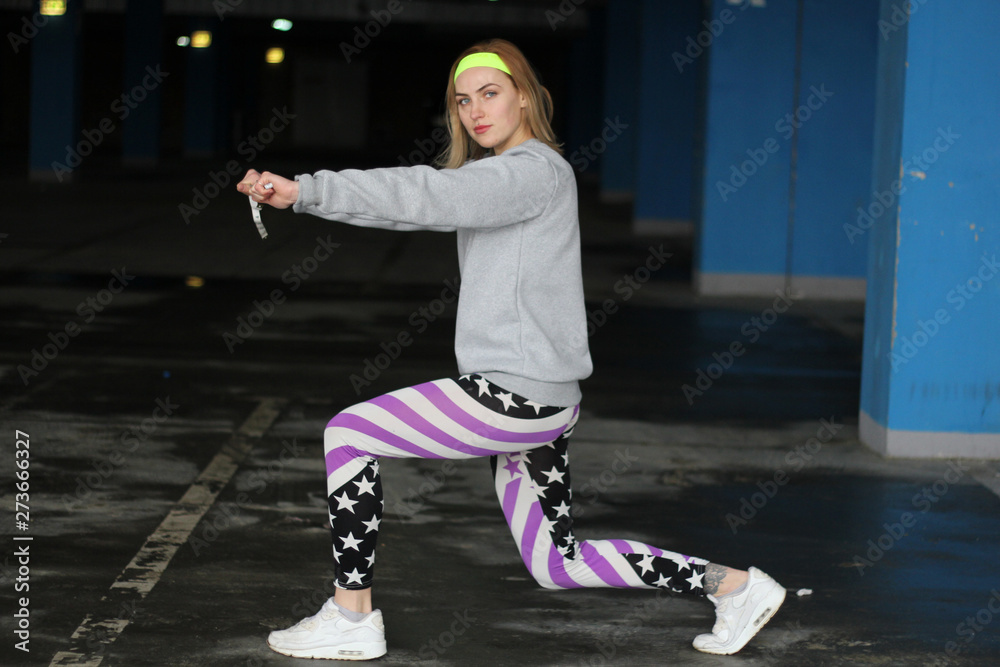 Girl is a blonde trainer in a gray thin. Street style. Advertising brand clothing. Fashion Shooting. Sentimental strip for swirling volume. Shopping cart in supermarket.