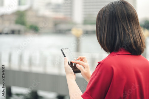 A beautiful Asian woman uses a smartphone in the city center to search for various places. Restaurant reviews And send a message with copy space.