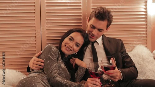 Beautiful woman in nice grey dress laughing at her man's jokes while drinkindg red wine in a hotel slow motion photo