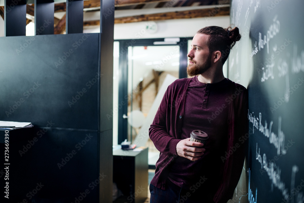Young businessman with coffee in office, having a break. Young businessman with coffee in office, having a break.