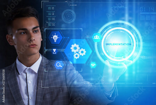 The concept of business, technology, the Internet and the network. A young entrepreneur working on a virtual screen of the future and sees the inscription: Implementation